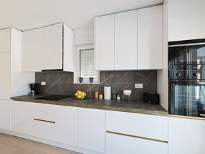 A modern kitchen with white cabinets, a marble countertop, and a built-in oven. - Villa IviCasa with pool by Interhome (Murvica)