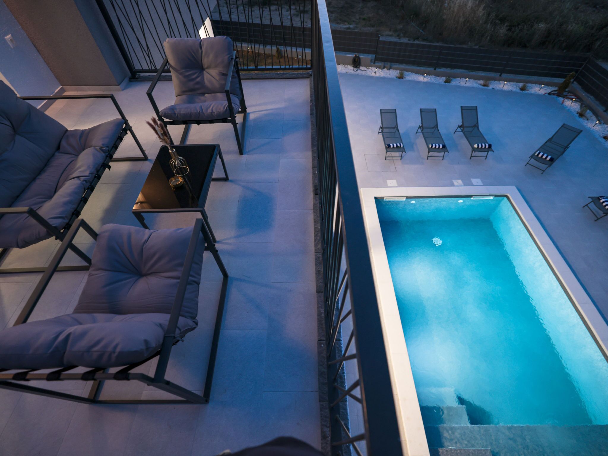 A rooftop pool area with lounge chairs and a table.