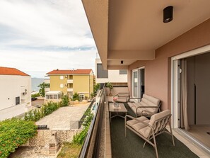 Ein Balkon mit Gartenmöbeln, Blick auf das Meer und angrenzende Gebäude.