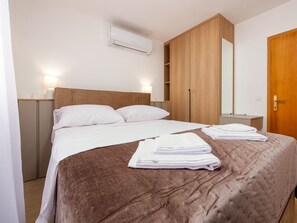 Ein Hotelzimmer mit Bett, Kleiderschrank, Spiegel und Tür.