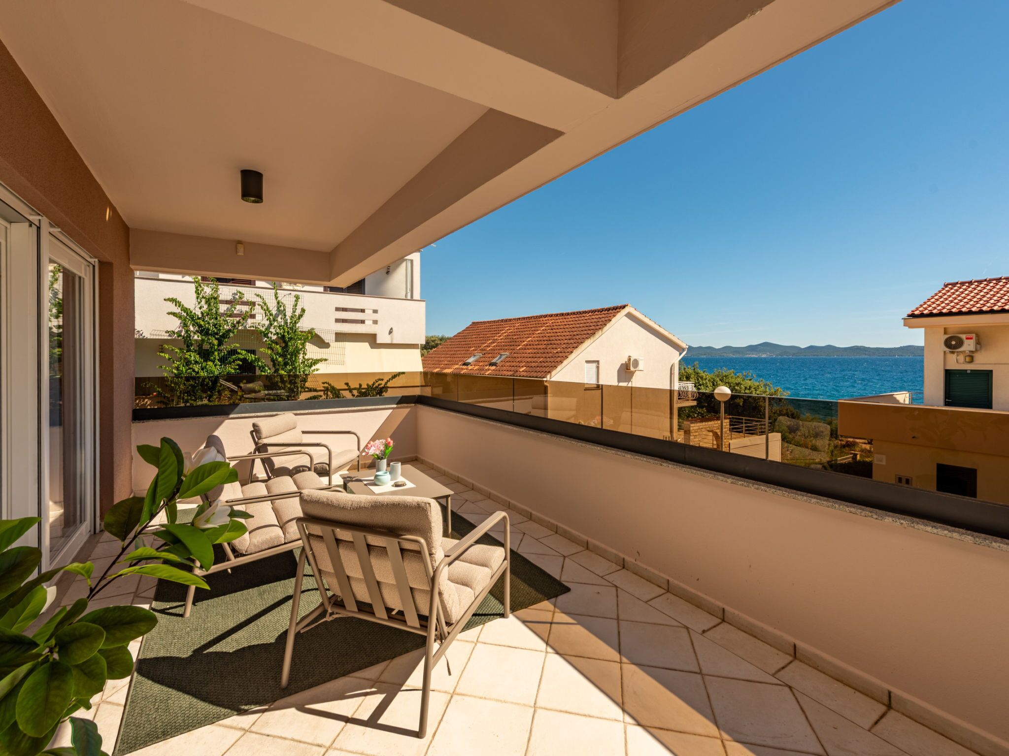 A balcony with a table, chairs, and a view of the sea.