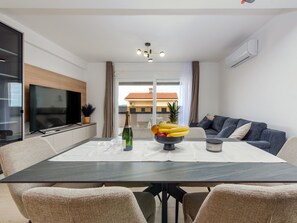A modern living room with a dining table, a sofa, and a TV. - Apartment  by Interhome (Zadar/Kožino)