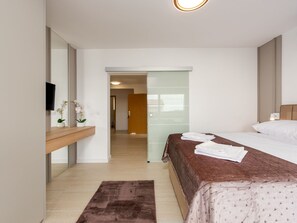 A modern hotel room with a bed, a bedside table, a mirror, and a view into the hallway. - Seaview apartment Casa Almaris A1 by Interhome (Zadar/Kožino)