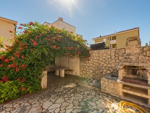 A stone patio with a stone wall, a barbecue grill, and a bench. - Seaview apartment Casa Almaris A3 by Interhome (Zadar/Kožino)
