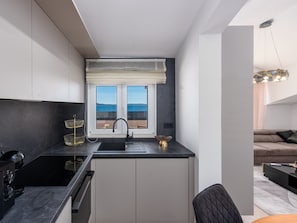 Une cuisine moderne avec vue sur la mer, un plan de travail noir et une fenêtre offrant un beau panorama.