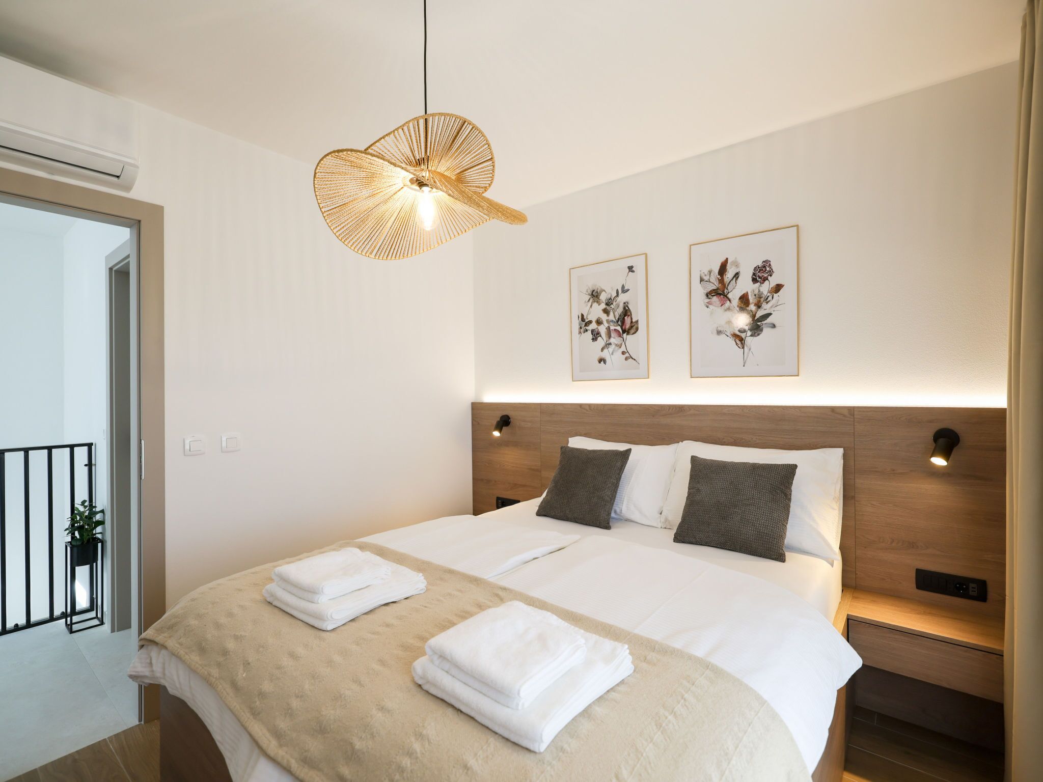 A hotel room with a bed, two wall-mounted light fixtures, and two framed floral artworks.