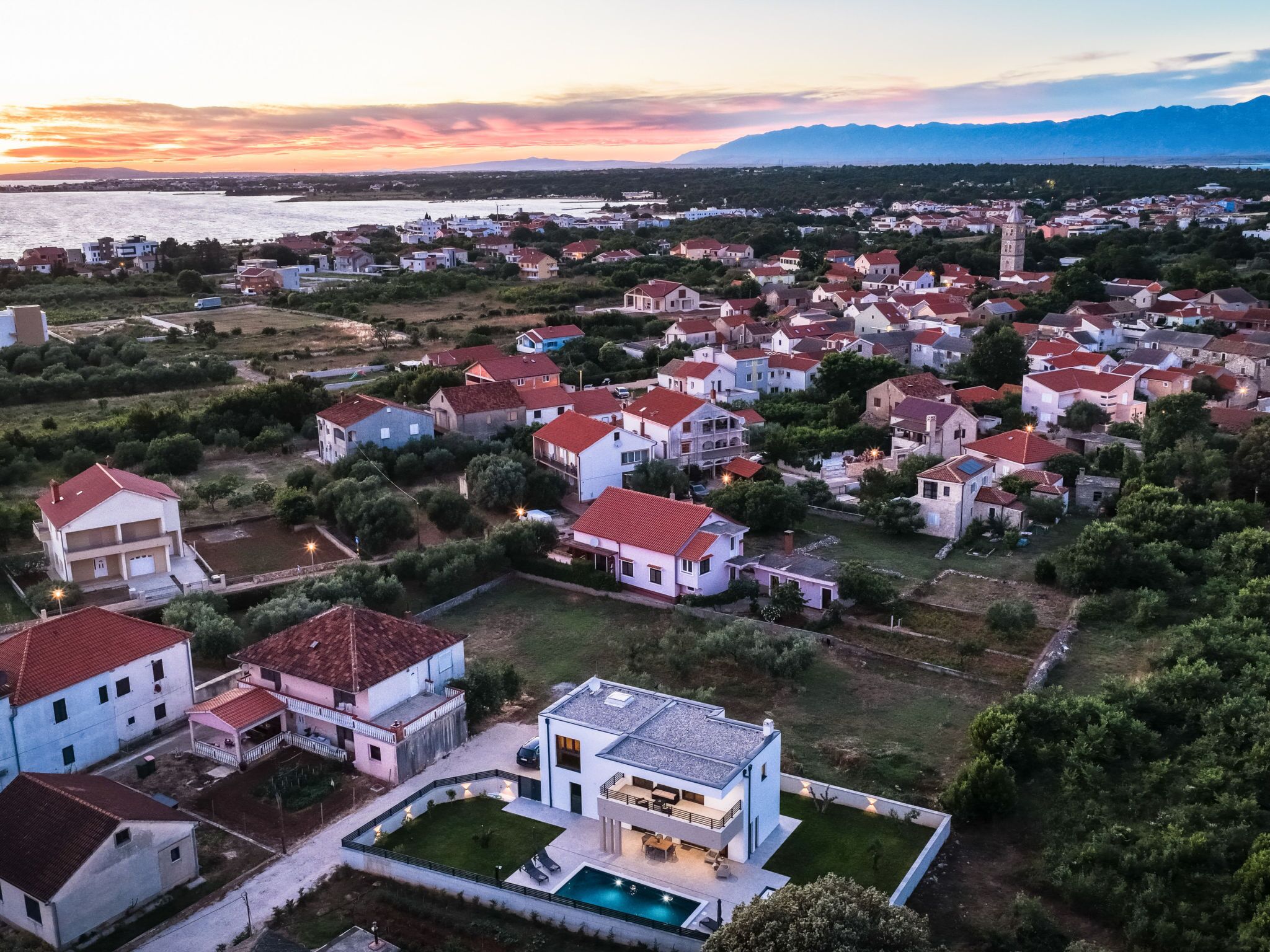 A residential area with houses, a swimming pool, and a distant mountain range.