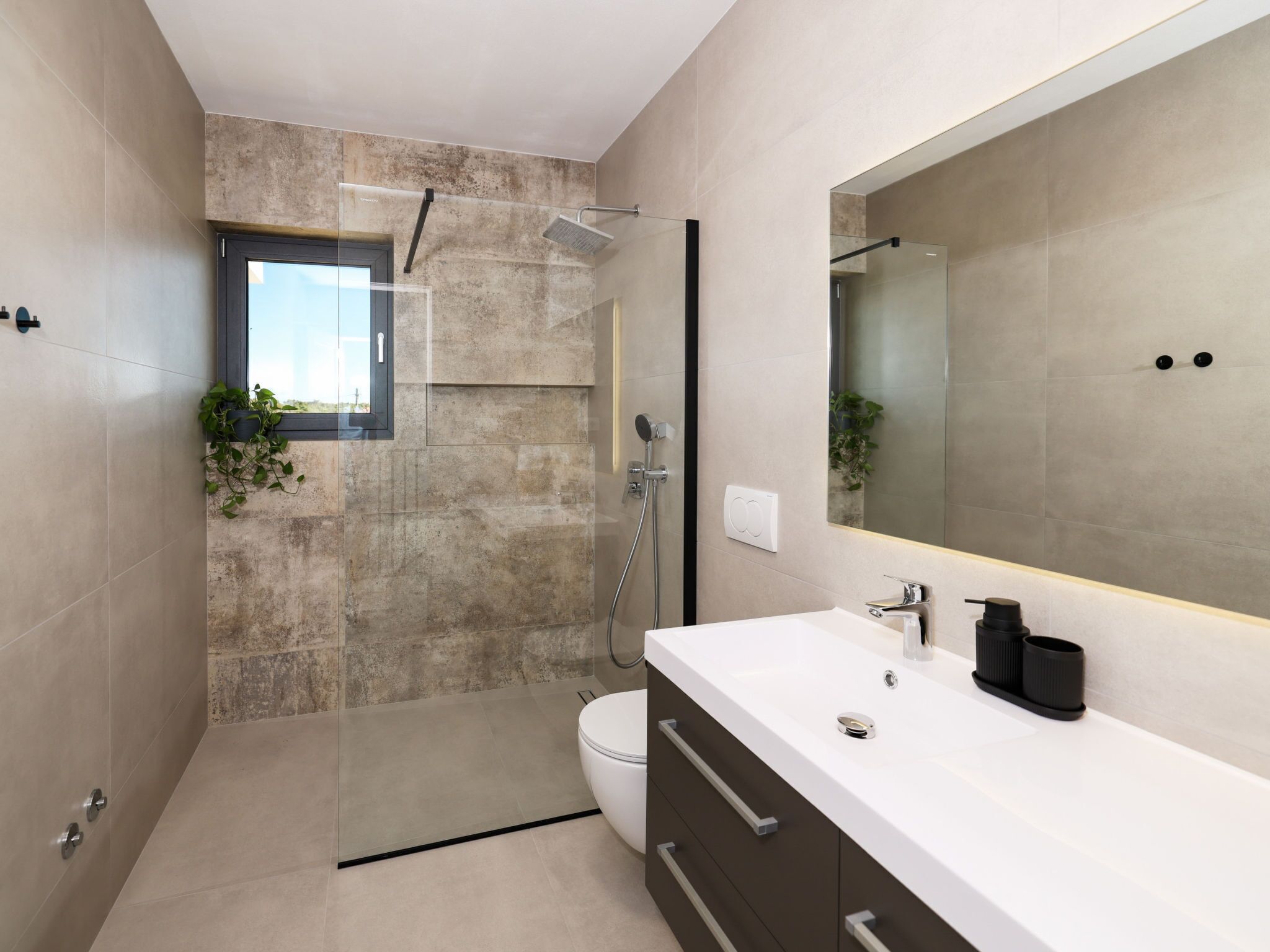 Une salle de bain moderne avec une douche à parois de verre, un lavabo blanc et un grand miroir.