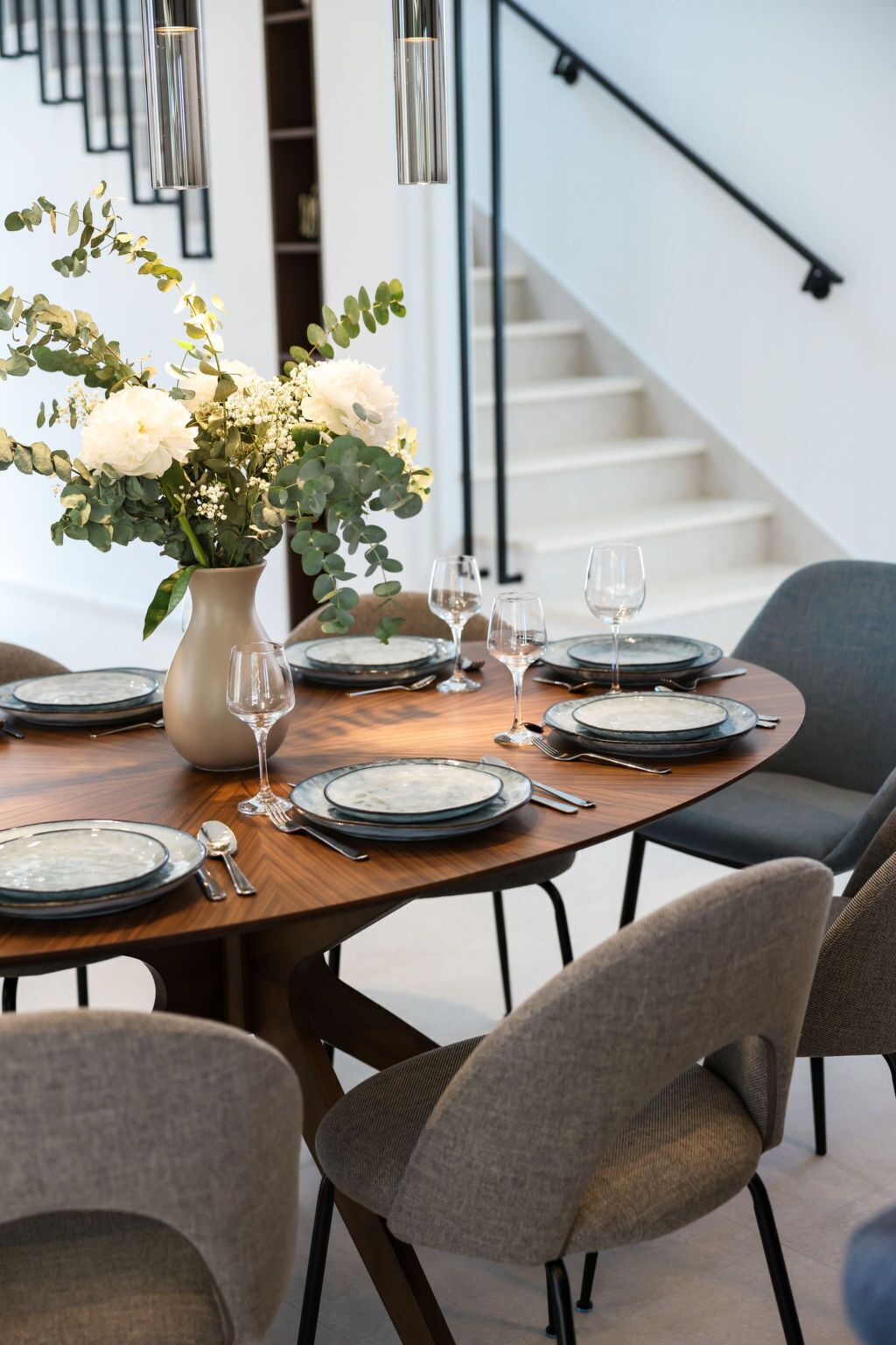 A dining table set with plates, glasses, and cutlery, accompanied by a vase of flowers.