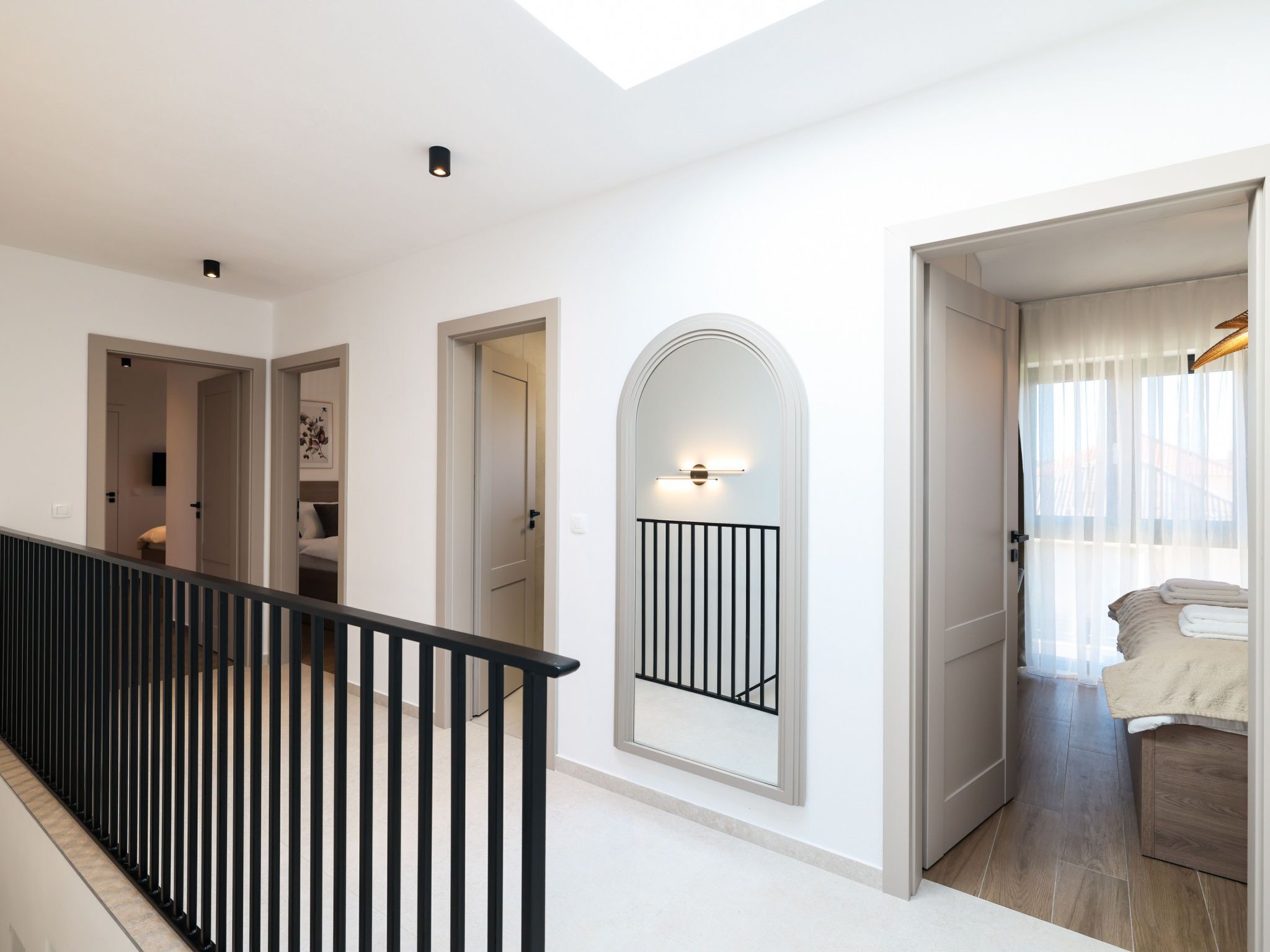 Un interior moderno con una escalera, un pasillo que conduce a un dormitorio y un balcón con vistas.