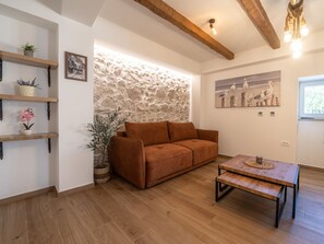A cozy living room with a stone wall, a brown sofa, wooden shelves, and a coffee table. - Holiday House Blažov Dvor with jacuzzi by Interhome (Zaton)