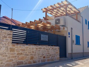 A stone wall with a wooden gate, a wooden pergola, and a building with a sign that reads 'Holiday House'. - Holiday House Blažov Dvor with jacuzzi by Interhome (Zaton)