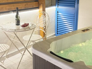 A hot tub with a glass enclosure, a table with a bottle and a bowl of fruit, and a chair with a decorative backrest. - Holiday House Blažov Dvor with jacuzzi by Interhome (Zaton)