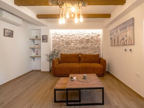 A living room with a sofa, a coffee table, a stone wall, and a painting of birds. - Holiday House Blažov Dvor with jacuzzi by Interhome (Zaton)