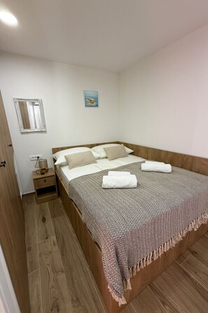 A bedroom with a wooden bed, a nightstand, a lamp, a mirror, and a painting on the wall. - Holiday House Blažov Dvor with jacuzzi by Interhome (Zaton)