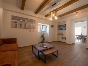 Een ruime woonkamer met een houten salontafel, een bank en een schilderij van vogels aan de muur.