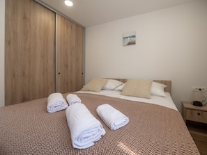 Une chambre d’hôtel avec un lit, une armoire en bois et une table de chevet.
