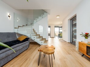 A modern living room with a grey sofa, a wooden coffee table, and a staircase with glass railings. - Seaview Villa Mar with pool, jacuzzi and sauna by Interhome (Privlaka)