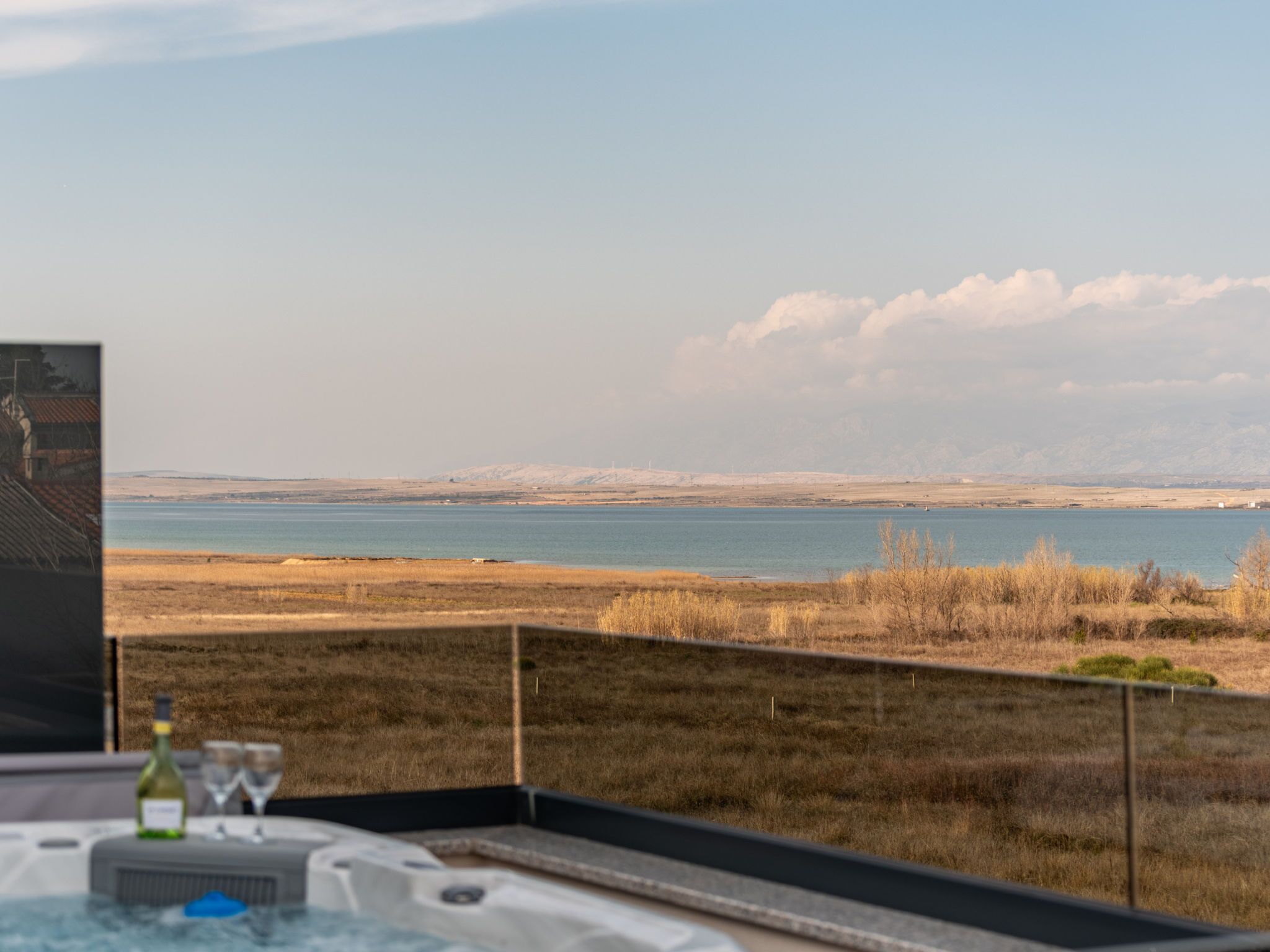 A dining area with a view of a body of water and distant hills.