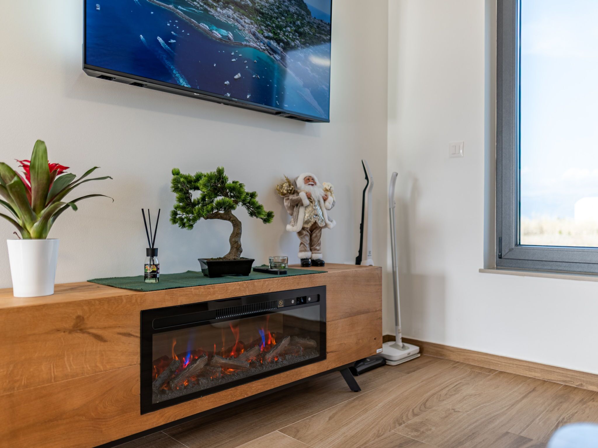 Un salon moderne avec un téléviseur à écran plat, une cheminée, un bonsaï, une figurine décorative et une plante en pot.