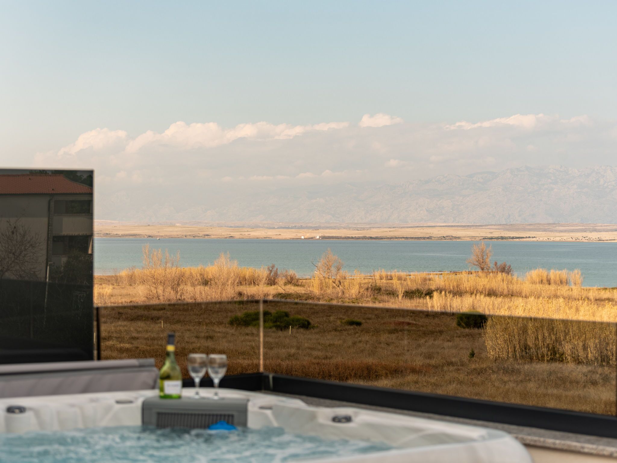 A hot tub with a view of a lake and mountains in the distance.