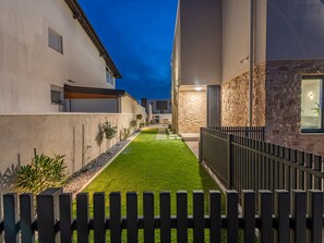 Ein modernes Wohnhaus mit befestigter Auffahrt, einer Steinmauer und einem Holzzaun.