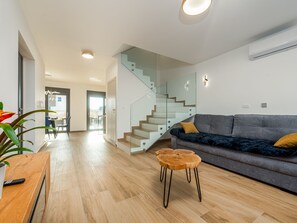 Ein modernes Wohnzimmer mit Treppe, einer Couch und einem Holztisch.