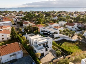 A residential area with modern houses, a paved driveway, and a view of the sea. - Luxury Villa Positiva with heated pool by Interhome (Vir)
