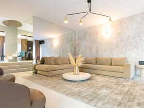 A modern living room with a sectional sofa, a round coffee table, and a large mirror. - Luxury Villa Positiva with heated pool by Interhome (Vir)