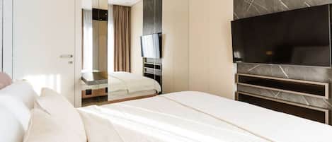 A modern hotel room with a large bed, a flat-screen TV mounted on a marble wall, and a wardrobe with a mirror.