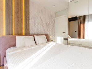 Ein Hotelzimmer mit einem großen Bett, einem Nachttisch, einem Spiegel und einem Kleiderschrank.