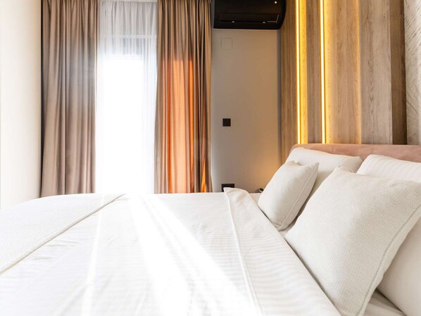 Une chambre d’hôtel avec un grand lit, des rideaux et un climatiseur fixé au mur.