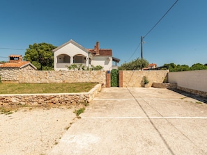 Ein Wohnhaus mit gepflasterter Auffahrt, einer Steinmauer und einem kleinen Garten.