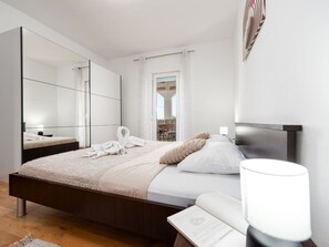 Ein modernes Schlafzimmer mit einem großen Bett, einem Nachttisch, einem Spiegel und einem Fenster mit Vorhängen.