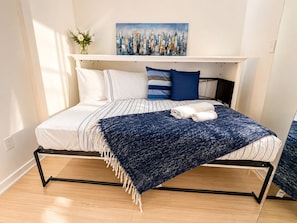 A bed with a striped bedspread, a blue throw blanket, and two pillows. - The Imperial Waterfront Escape (Toronto)