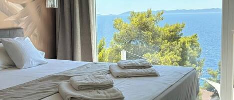 A bedroom with a large bed, a view of the sea, and a modern design.
