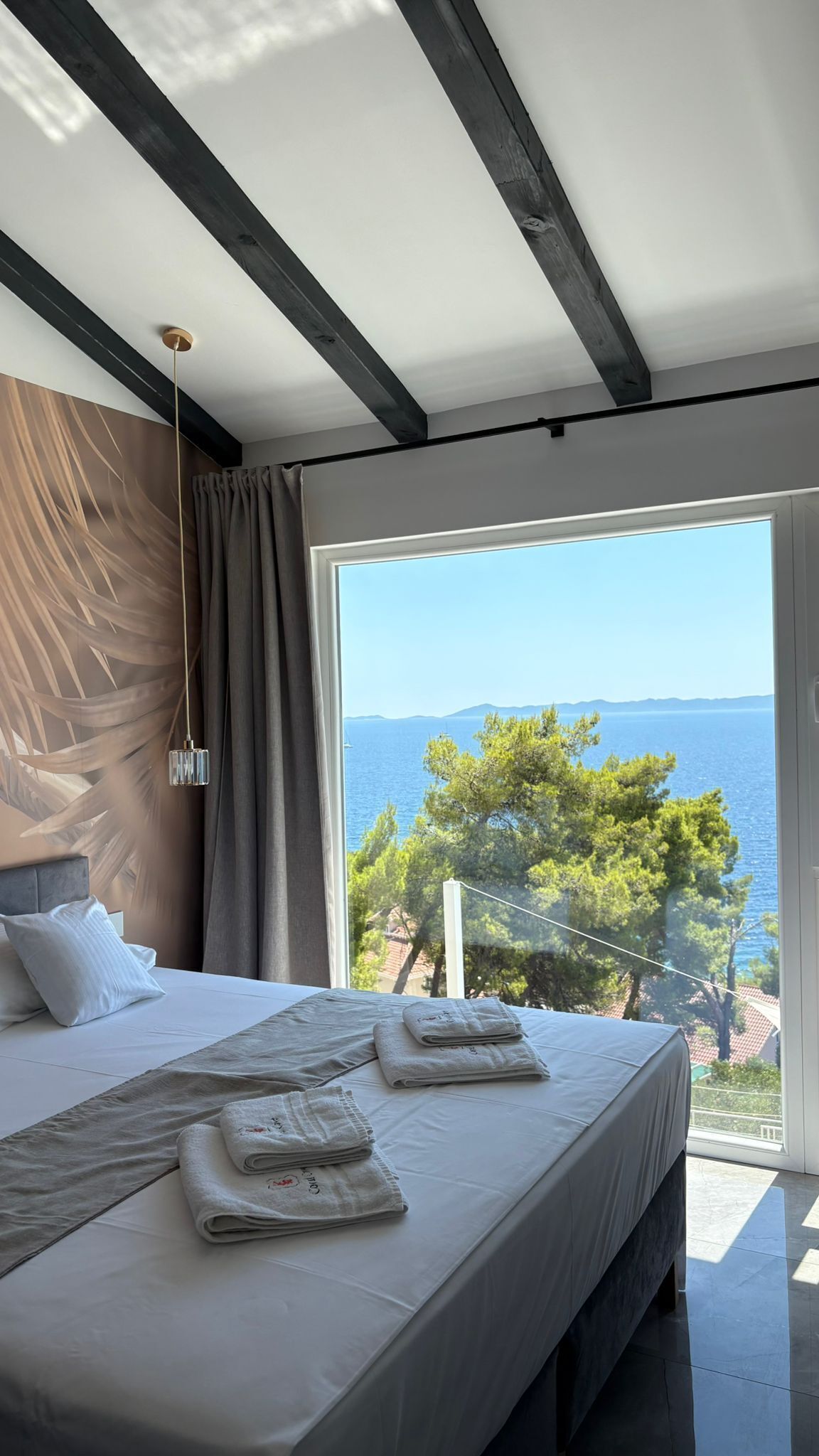 Un dormitorio con cama, lámpara colgante y vista al mar.