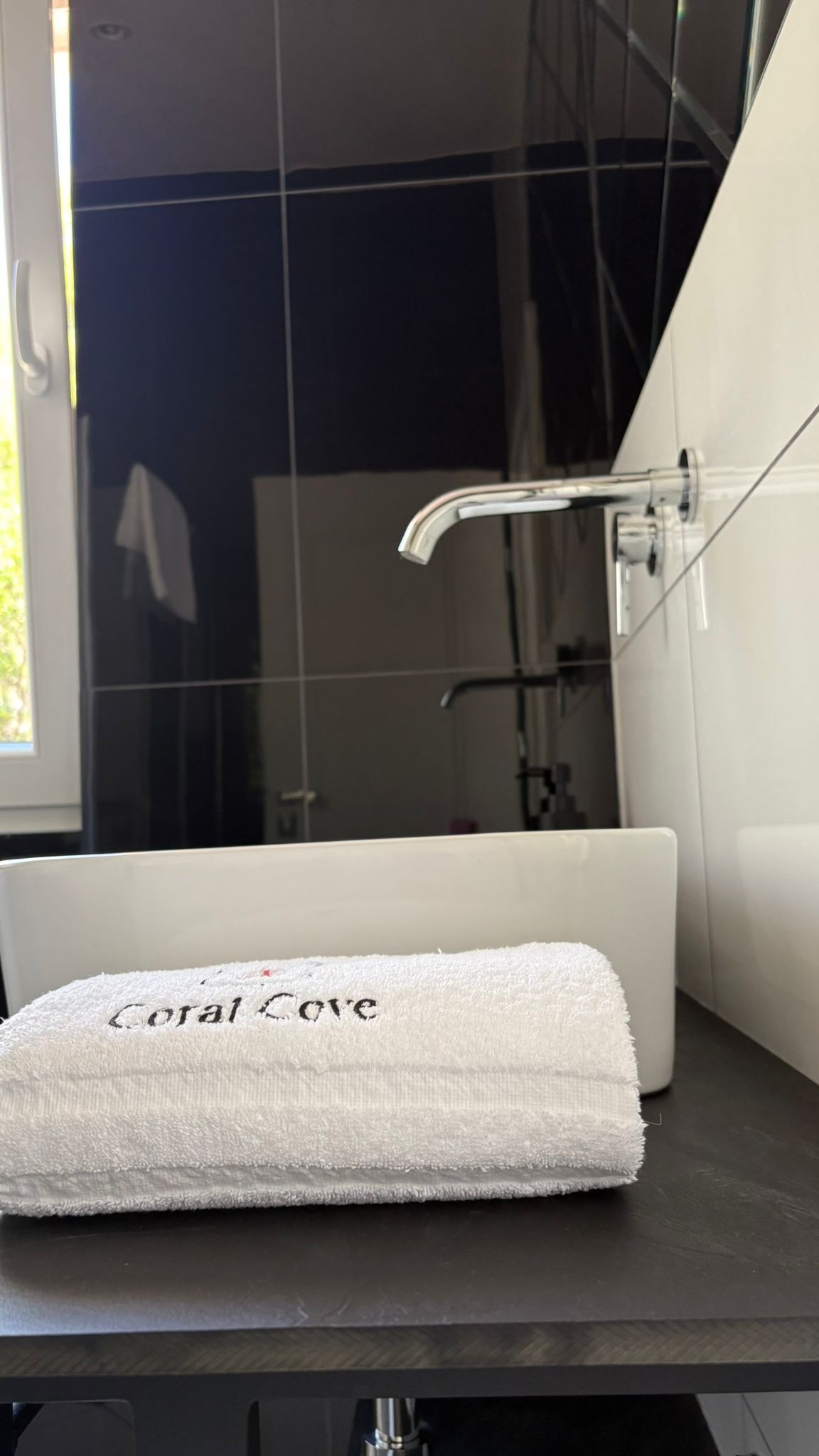 Un baño con una bañera blanca, una toalla con la etiqueta 'Coral Cove' y una zona de ducha.