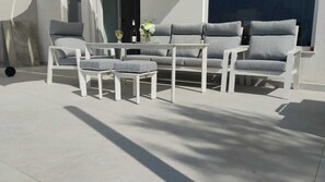A modern outdoor seating area with a sofa, two chairs, and a small table. - Coral Cove 1 (Blato)