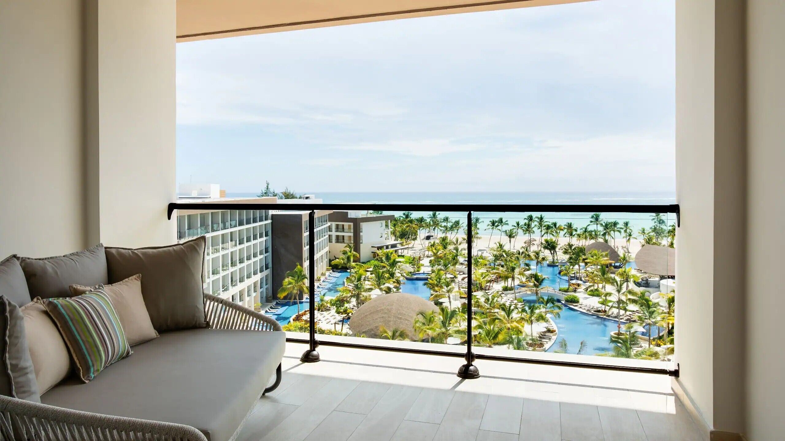 A balcony with a view of a resort pool and palm trees.