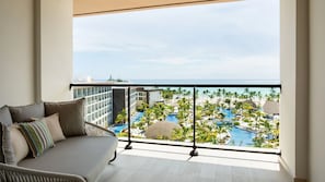 Un balcón con vista a la piscina de un complejo turístico y palmeras.