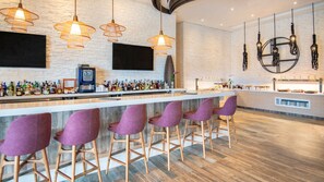 A bar area with a long counter, multiple liquor bottles, a coffee machine, and purple bar stools. - Unforgettable Cap Cana Retreat for All Ages (Punta Cana)