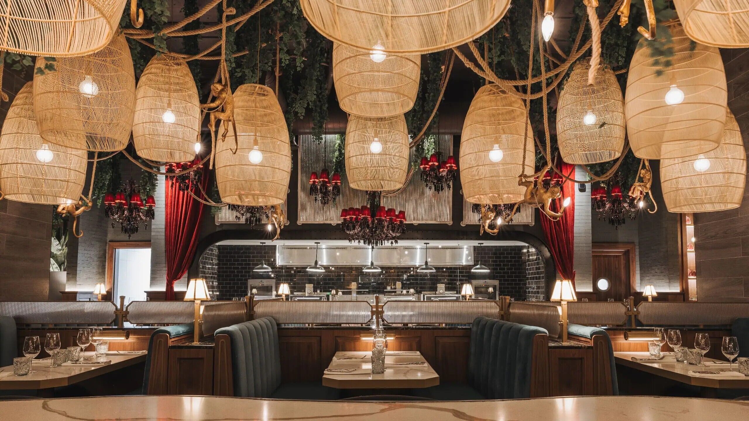 A restaurant interior with high ceilings, hanging wicker lamps, and a bar area with stools and tables.