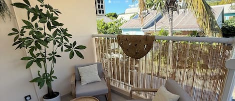 Un espace extérieur moderne aménagé avec un canapé, une table ronde en bois et une plante en pot.