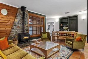 Ein gemütliches Wohnzimmer mit Steinwand, Kamin und Essbereich mit Tisch und Stühlen.