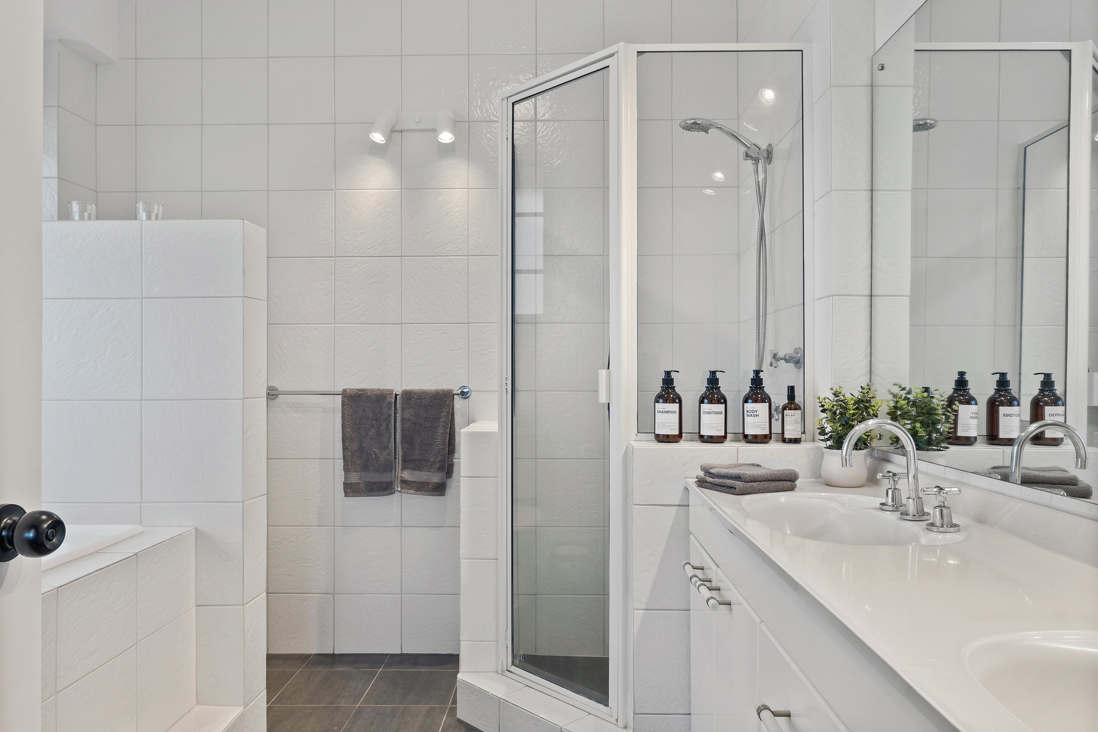 A modern bathroom with a shower, a large mirror, and toiletries.