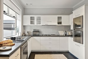 A modern kitchen with white cabinetry, a stainless steel range, and a built-in oven.