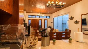 A modern kitchen with wooden cabinets, a marble countertop, and pendant lighting.