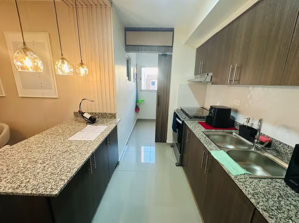 A kitchen with granite countertops, stainless steel appliances, and pendant lighting.