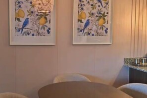A room with a bed, a chair, and two framed pictures on the wall.